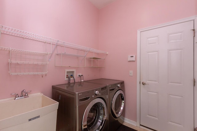 washroom with laundry area, washer and dryer, and a sink