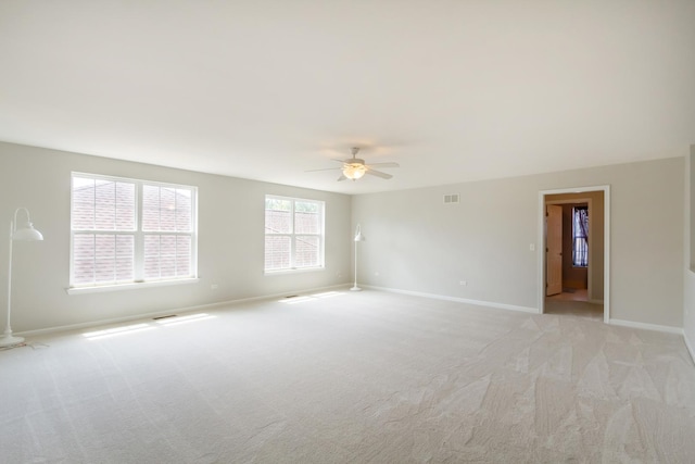 spare room with ceiling fan, baseboards, visible vents, and light carpet