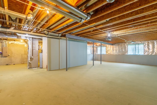 basement with electric panel, heating unit, and gas water heater