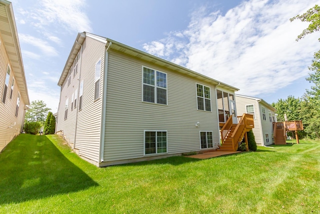 rear view of house with stairway, a wooden deck, and a yard