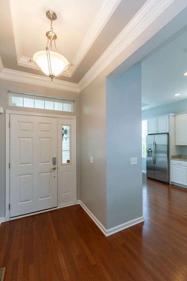 foyer entrance with a tray ceiling, baseboards, dark wood-style flooring, and crown molding