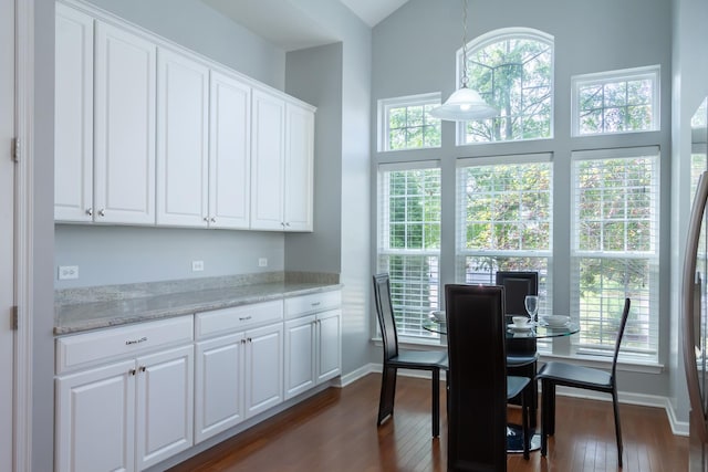 dining area featuring baseboards, dark wood-style flooring, and vaulted ceiling