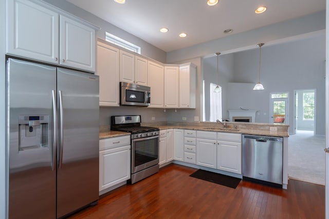 kitchen featuring open floor plan, white cabinets, stainless steel appliances, and a sink