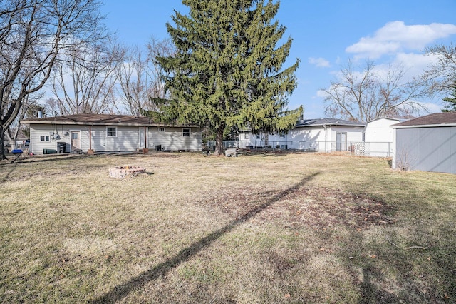 view of yard featuring an outbuilding, an outdoor fire pit, a shed, and fence