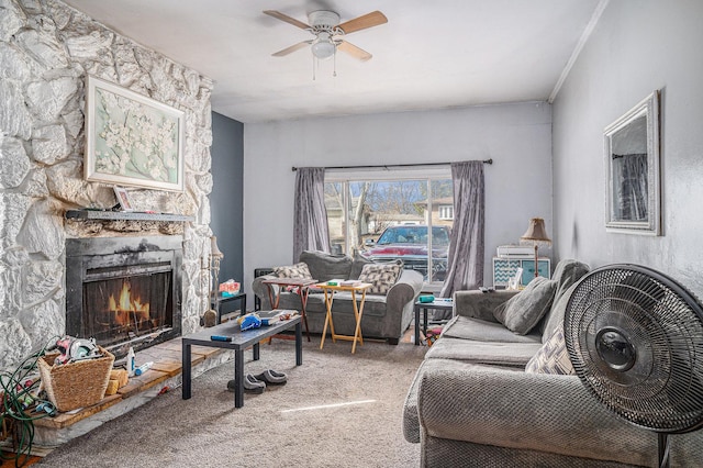 carpeted living area featuring a stone fireplace, a ceiling fan, and ornamental molding