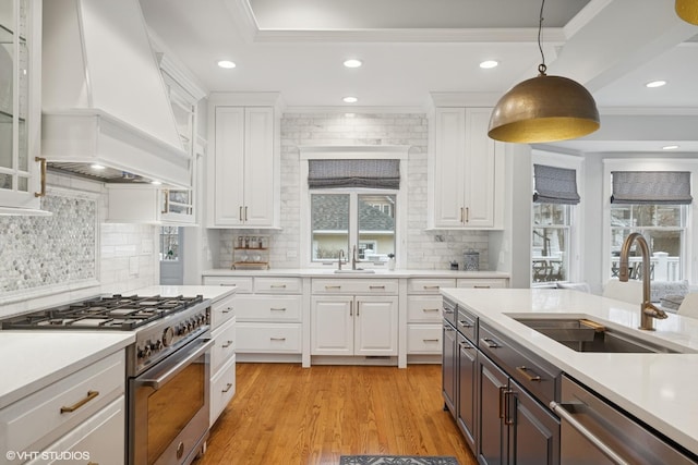 kitchen with a sink, custom exhaust hood, white cabinets, and stainless steel appliances