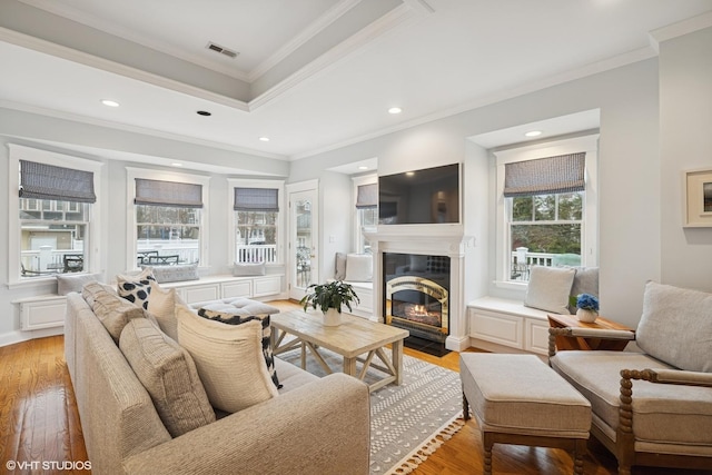 living area with recessed lighting, light wood-type flooring, a tiled fireplace, and crown molding