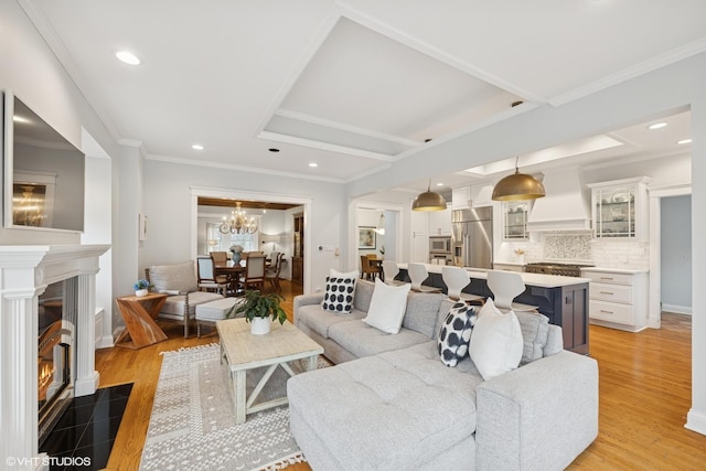 living area featuring recessed lighting, a fireplace with flush hearth, light wood-style flooring, and ornamental molding