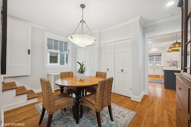 dining area with light wood finished floors, baseboards, and ornamental molding