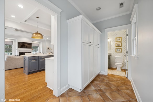 corridor with visible vents, baseboards, recessed lighting, a sink, and crown molding