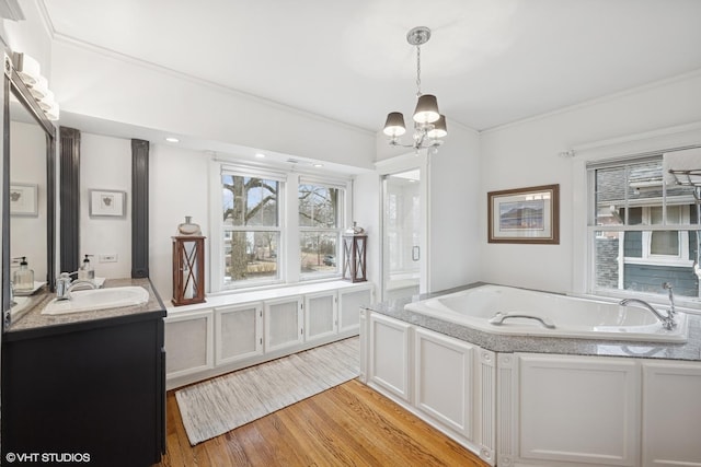 full bathroom featuring a garden tub, ornamental molding, an inviting chandelier, wood finished floors, and vanity