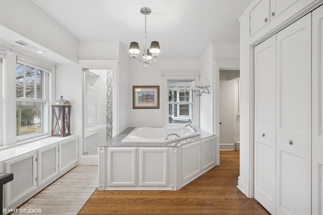 bathroom with a shower stall, a healthy amount of sunlight, a garden tub, and wood finished floors