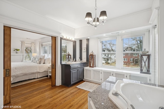 bathroom with crown molding, a wealth of natural light, wood finished floors, and ensuite bathroom