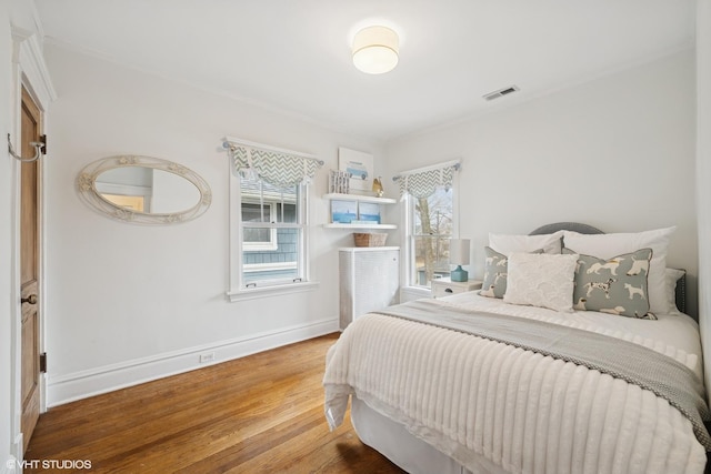 bedroom featuring wood finished floors, visible vents, and baseboards