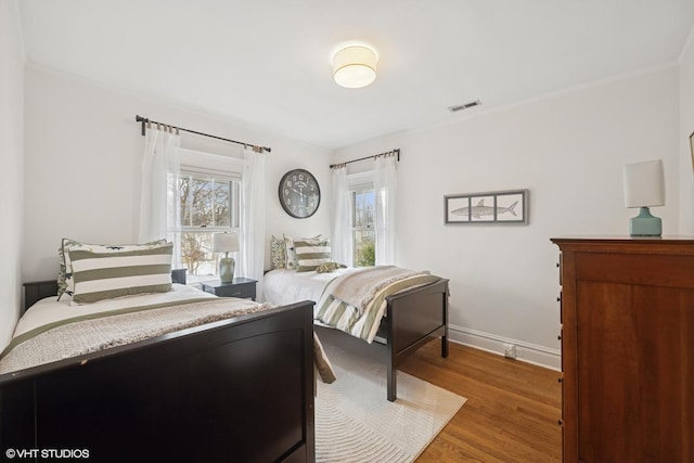 bedroom with wood finished floors, visible vents, and baseboards