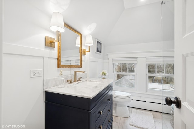 bathroom with vanity, a baseboard radiator, vaulted ceiling, wainscoting, and toilet