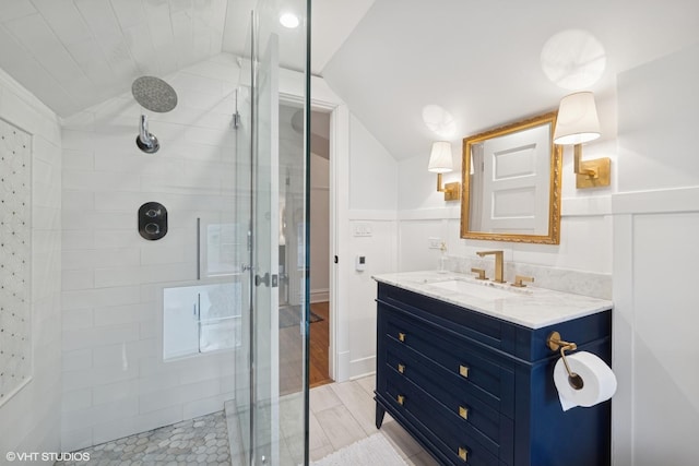 bathroom featuring vanity, wood finished floors, a shower stall, and vaulted ceiling