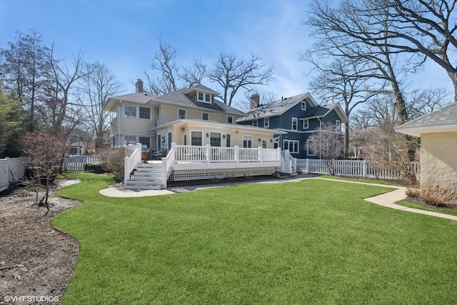 rear view of house with a yard, a wooden deck, a fenced backyard, and a chimney