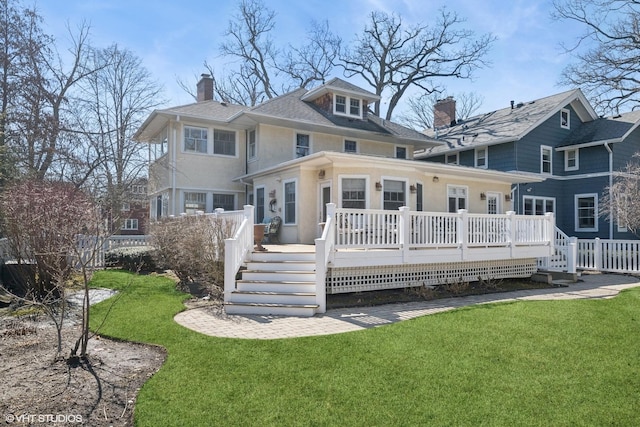 rear view of house featuring a wooden deck, a yard, fence, and a chimney