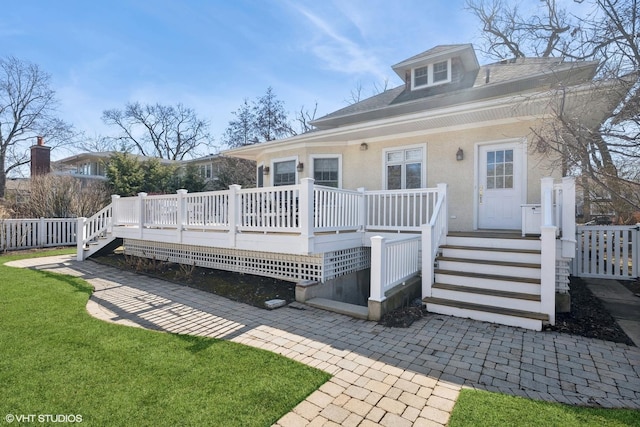 rear view of house with stucco siding and a lawn