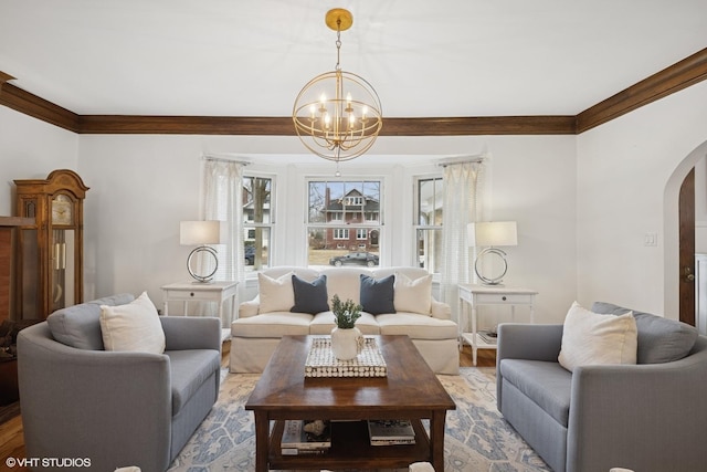 living room featuring a notable chandelier, wood finished floors, arched walkways, and ornamental molding