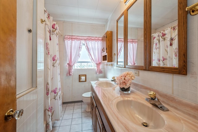 full bath featuring tile walls, toilet, double vanity, and a sink