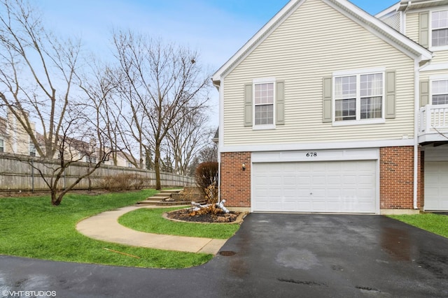 view of side of home featuring brick siding, an attached garage, aphalt driveway, and fence