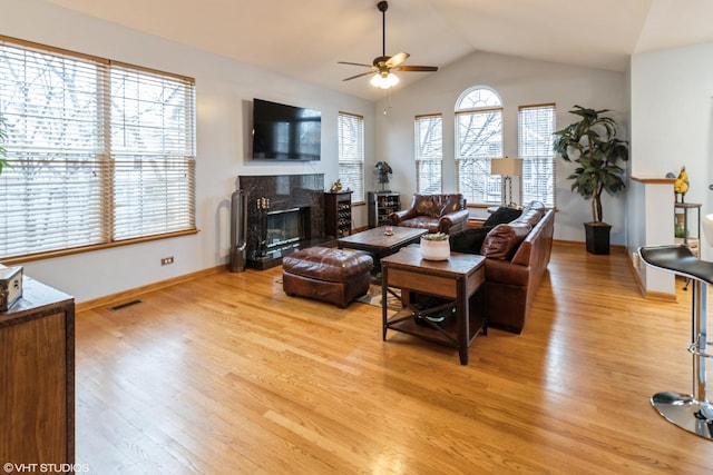 living area featuring visible vents, lofted ceiling, a fireplace, and light wood finished floors