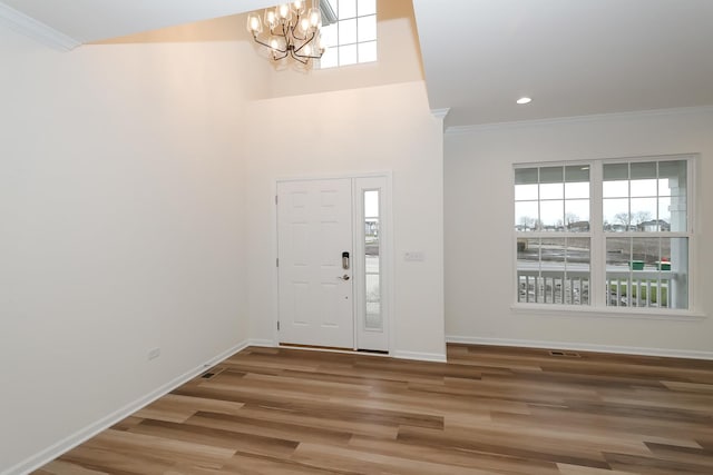 entryway with baseboards, wood finished floors, an inviting chandelier, and ornamental molding
