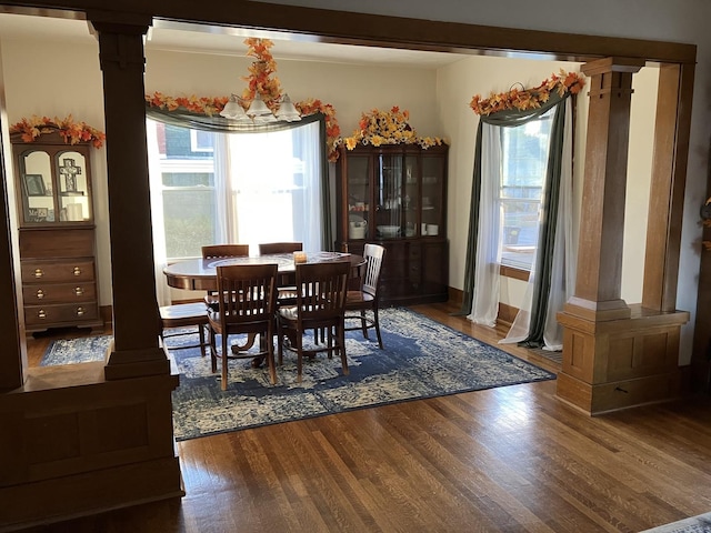 dining area featuring wood finished floors and decorative columns