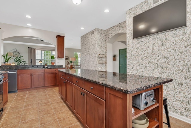 kitchen with open shelves, wallpapered walls, a sink, arched walkways, and visible vents