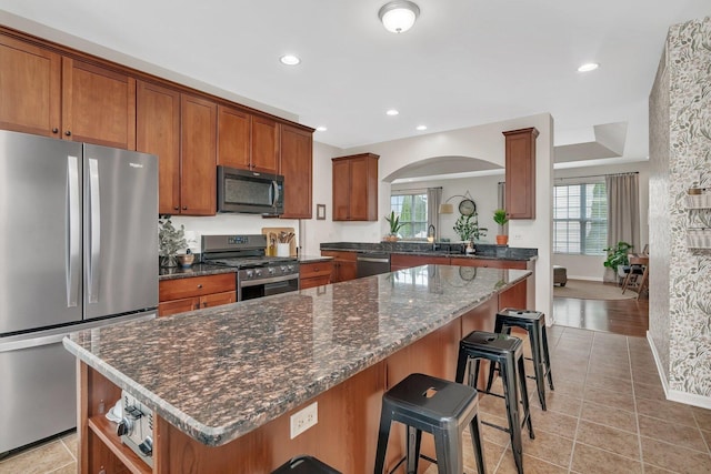 kitchen featuring a healthy amount of sunlight, brown cabinetry, a breakfast bar, and stainless steel appliances