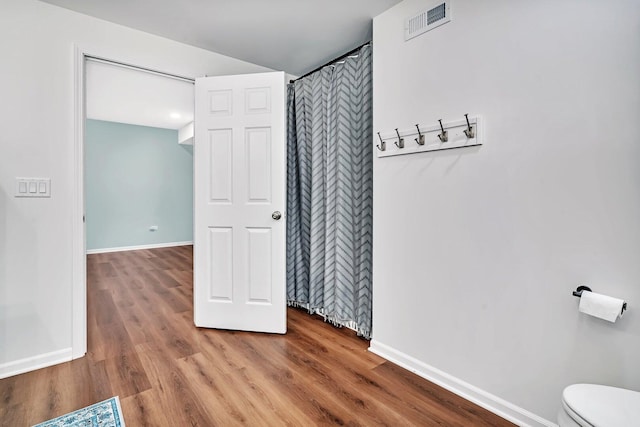 interior space with baseboards, visible vents, and wood finished floors