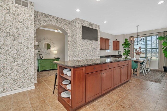 kitchen featuring open shelves, an inviting chandelier, a kitchen island, arched walkways, and visible vents