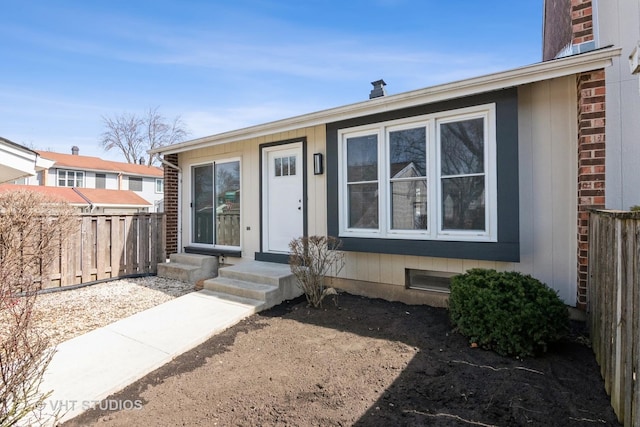 view of front of home featuring entry steps, fence, and brick siding