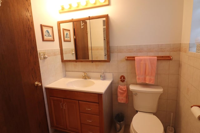 half bathroom with tile walls, wainscoting, toilet, and vanity