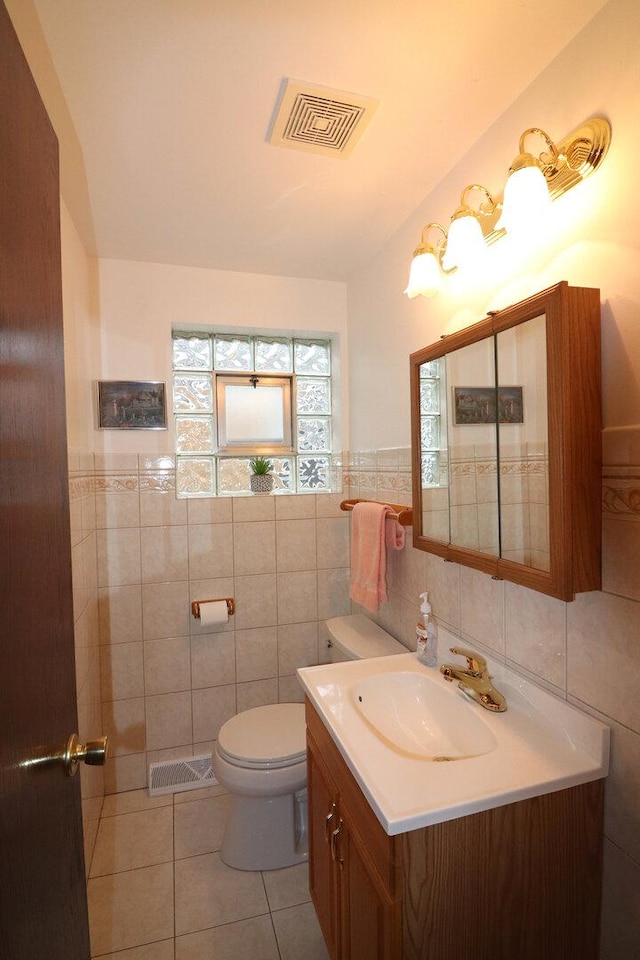 bathroom with tile patterned flooring, tile walls, toilet, and visible vents