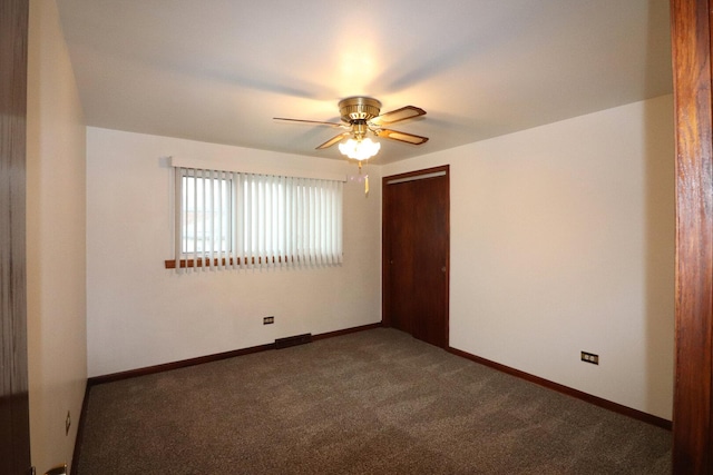 spare room featuring dark colored carpet, baseboards, and ceiling fan