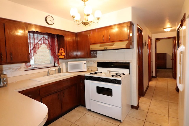 kitchen featuring white appliances, light countertops, under cabinet range hood, and a sink