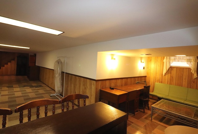 dining area with stairs, wooden walls, and a wainscoted wall