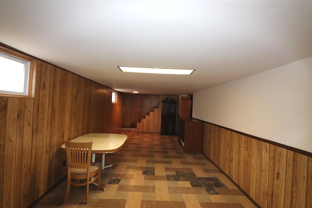 corridor with wainscoting, stairway, wood walls, and light floors