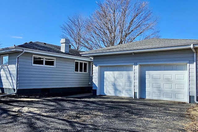 view of home's exterior featuring a shingled roof, a garage, and a chimney