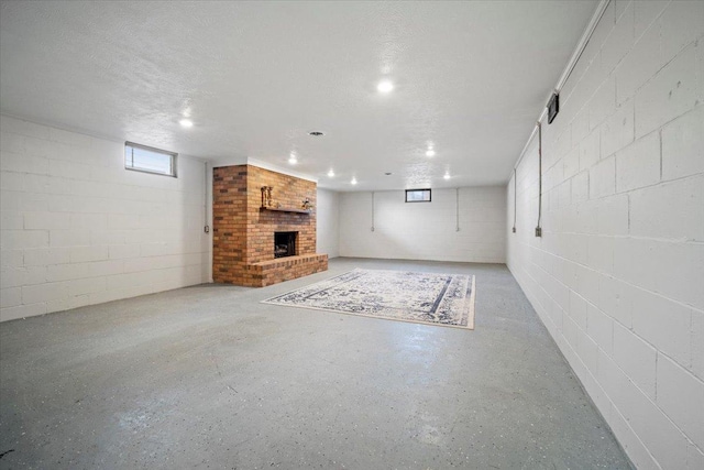 below grade area featuring a brick fireplace, visible vents, and a textured ceiling