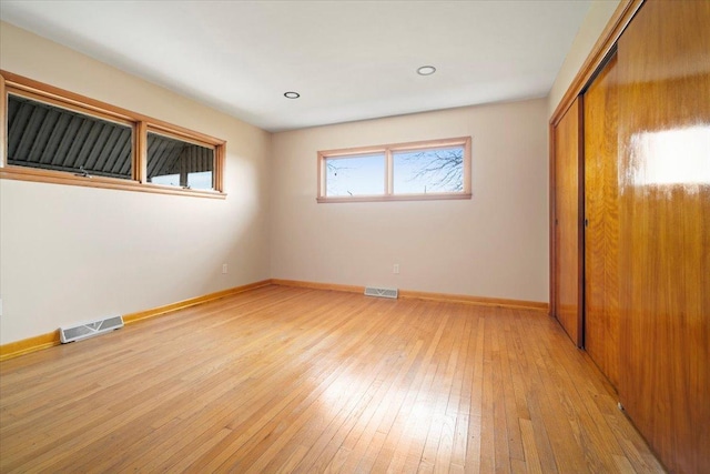 unfurnished bedroom with visible vents, baseboards, a closet, and light wood-style flooring