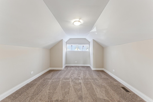 bonus room featuring lofted ceiling, carpet flooring, baseboards, and visible vents