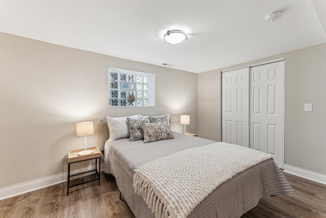 bedroom with dark wood-type flooring, baseboards, visible vents, and a closet