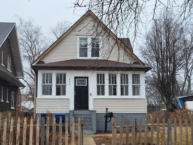 bungalow featuring entry steps, roof with shingles, and fence