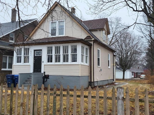 view of front of house featuring roof with shingles, a fenced front yard, and a chimney