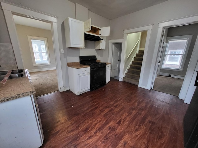 kitchen featuring a sink, black gas stove, under cabinet range hood, white cabinetry, and dark wood-style flooring