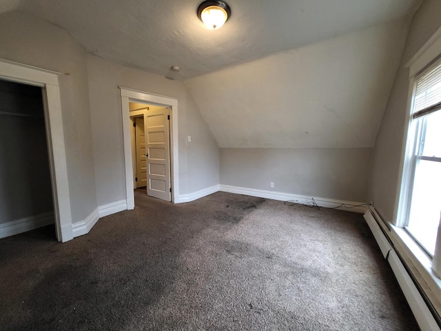 bonus room featuring baseboards, dark carpet, vaulted ceiling, baseboard heating, and a textured ceiling